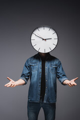 Wall Mural - Man with clock on head pointing with hands on grey background, concept of time management