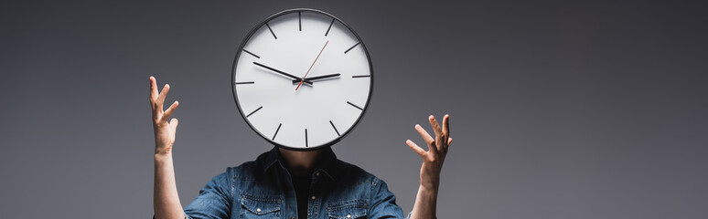 Wall Mural - Horizontal image of man with clock on head gesturing on grey background, concept of time management
