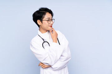 Doctor Asian woman over isolated blue background looking side