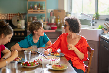 The family gathers around the table in the kitchen to enjoy the delicious strawberry tart that Mom just made.