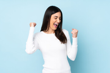 Young caucasian woman isolated on blue background celebrating a victory