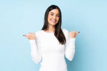 Wall Mural - Young caucasian woman isolated on blue background with thumbs up gesture and smiling