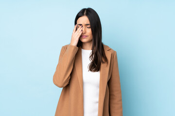 Young caucasian woman isolated on blue background with headache