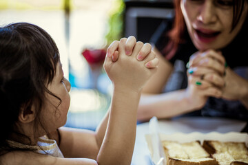 Asian woman and little girl praying on the table.