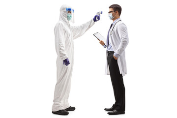 Wall Mural - Full length profile shot of a man in a hazmat suit measuring temperature to a doctor