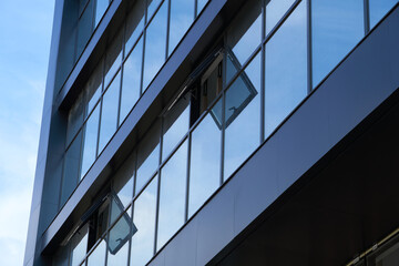 facade of a modern building on a bright Sunny day, blue sky and clouds reflecting in a glass, beautiful exterior of the new building