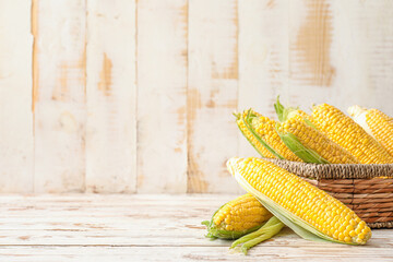 Basket with fresh corn cobs on table