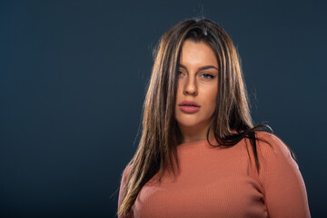 Close up portrait of beautiful young female model with orange blouse on black background