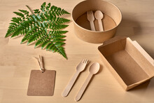 Top View Of Recyclable Carton Food Package And Wooden Fork And Knife Placed On Table With Fern Leaf