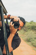 © Jorge Moya/ADDICTIVE STOCK - Happy traveling male with professional photo camera taking photos of wildlife during safari