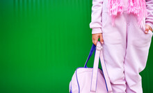 A Little Girl Is Holding A School Bag By The Straps, Dressed In A Pink Jumpsuit.