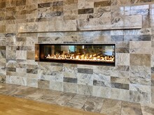 View Of Beautiful Lit Gas Fireplace Surrounded By Modern Tile