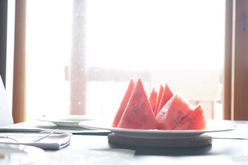 Close-up of fresh slices of red watermelon on plate on table with sunlight background