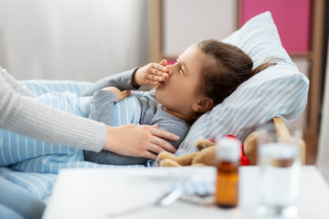 Sticker - family, health and people concept - mother and sick little daughter lying in bed at home