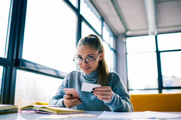 Portrait of professional marketing manager dialing number from visit card calling to banking service.Attractive business woman using information from card for searching web site of modern store