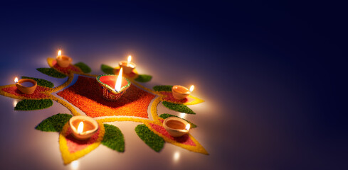 Wall Mural - Happy Diwali, Diya oil lamps lit on colorful rangoli with copy space