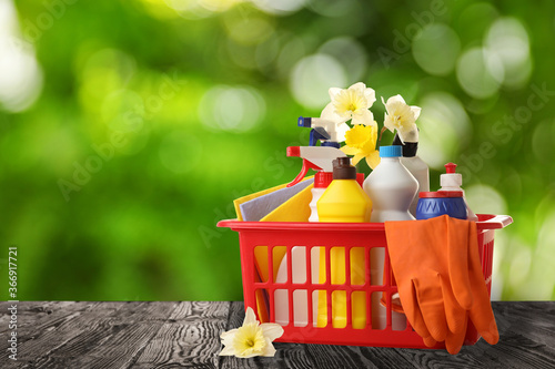 Cuadros en Lienzo Basket with cleaning supplies on wooden surface outdoors