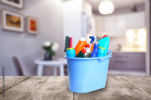 Fotografía Bucket with cleaning supplies on wooden surface in modern room
