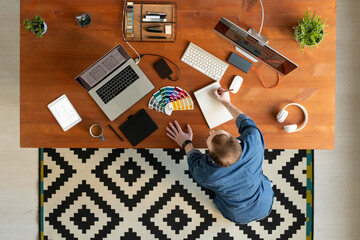 Wall Mural - High angle view of man in denim shirt standing at desk and making ui design sketch in notepad