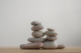 Fototapeta Desenie - Simplicity stones cairns isolated on white background, group of light gray pebbles built in towers, wood table