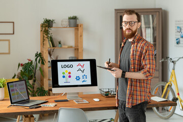 Wall Mural - Portrait of confident freelance brand designer with beard drawing on digitizer table in home office