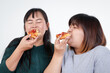 © SUPERMAO - Two Asian fat women are eating pizza happily. But has a negative effect on the body. The concept of weight loss, healthy food choices and healthy, white background.