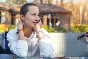 Young adult beautiful attractive stylish short haired woman enjoy sitting in street urban cafe, dau-dreaming and looking with hope. Positive deep in thought girl portrait in autumn park outdoors