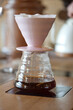 ceramic v60 filter drip pot with black coffee on table, closeup with blurred background, no people