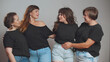 © TommyStockProject - Cheerful plus size women in black t-shirts and jeans embracing and smiling at camera