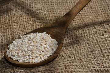 pearl barley with wooden spoon close up surface top view background