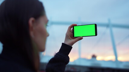 Girl taking picture on cellphone with green screen. Lady using mobile phone