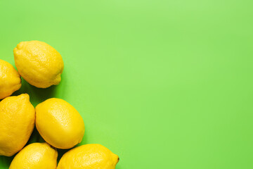 top view of ripe yellow lemons on green background with copy space