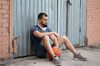 © Vladimir - Man rests on the street near a wall after playing basketball