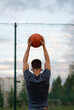 © Vladimir - Man stands with his back against the background of a sports field and holds a basketball in his hands