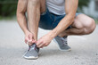 © Vladimir - Sporty man ties the laces on his sneakers before running on the street close up