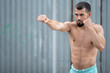 © Vladimir - Athlete conducts a fight with the shadow. A boxer trains punches on the street
