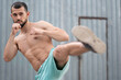 © Vladimir - Athlete is fighting with a shadow. Kickboxer trains kicks in the street