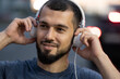 © Vladimir - Man with headphones listens to music late at night on a city street close up
