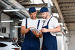 © LIGHTFIELD STUDIOS - happy mechanics in uniform looking at digital tablet in workshop