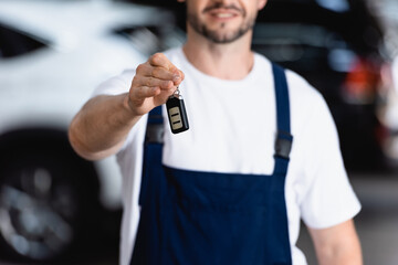 Wall Mural - selective focus of cheerful mechanic in uniform holding car key