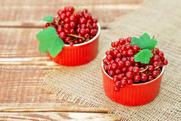 Wall Mural - Red currant berries in a cocotte bowl on a wooden background with burlap. Natural vitamins concept.