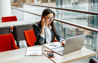 Girl works on a laptop in the workplace. Successful business woman creates a startup and makes decisions.