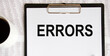 © Veranika - The word errors written with a pencil on white paper. An eraser from a pencil is starting to erase the word errors.