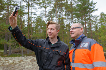 Portrait of happy mature man and young man together taking selfie in the forest