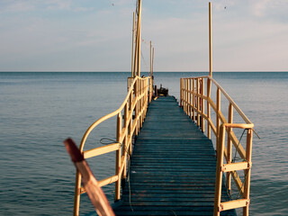 Wall Mural -  blue wooden footbridge with yellow railings leads into the Baltic Sea