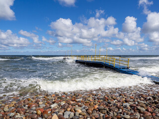 Wall Mural -  blue wooden footbridge with yellow railings leads into the Baltic Sea