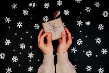 Wall Mural - woman holding a new year gift on black color background snowflakes and glitters
