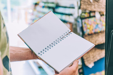 The guy holds a notebook in his hands in a creative store.