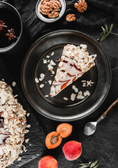 Wall Mural - Almond cake with fresh apricot, nuts, and baking ustensils on dark background. Holiday cake, delecious sweets and dessert, top up view