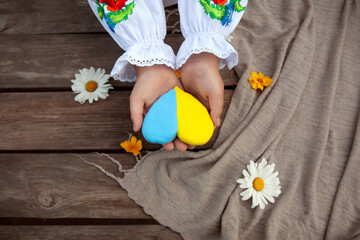 Hands child makes 
yellow and blue heart for the independence day of Ukraine. Step 9 Step by step instructions. DIY summer project.  The creative process. Kindergarten and school development. 